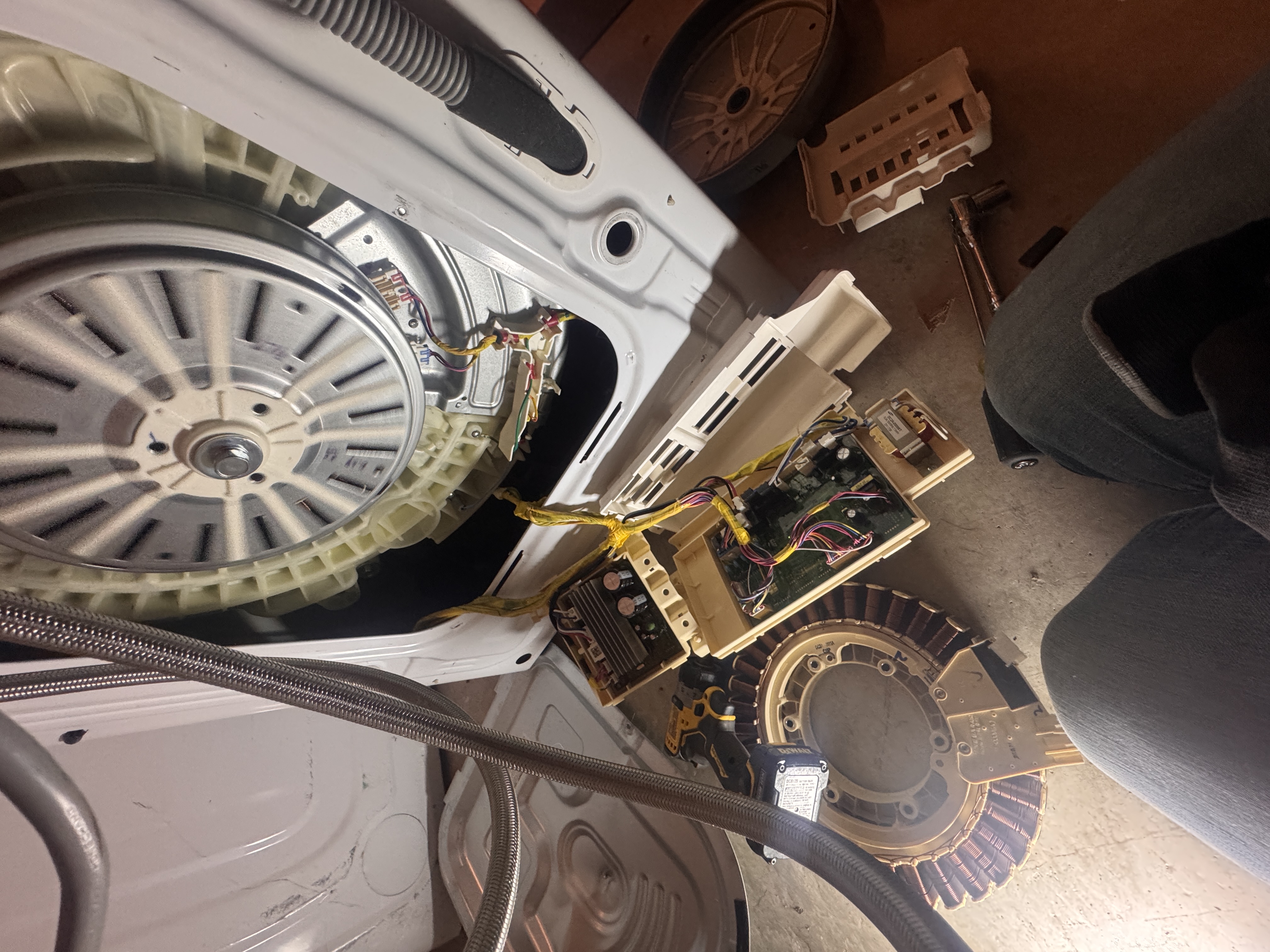 Complete front-load washer teardown — motor, bearings, control boards on the floor
